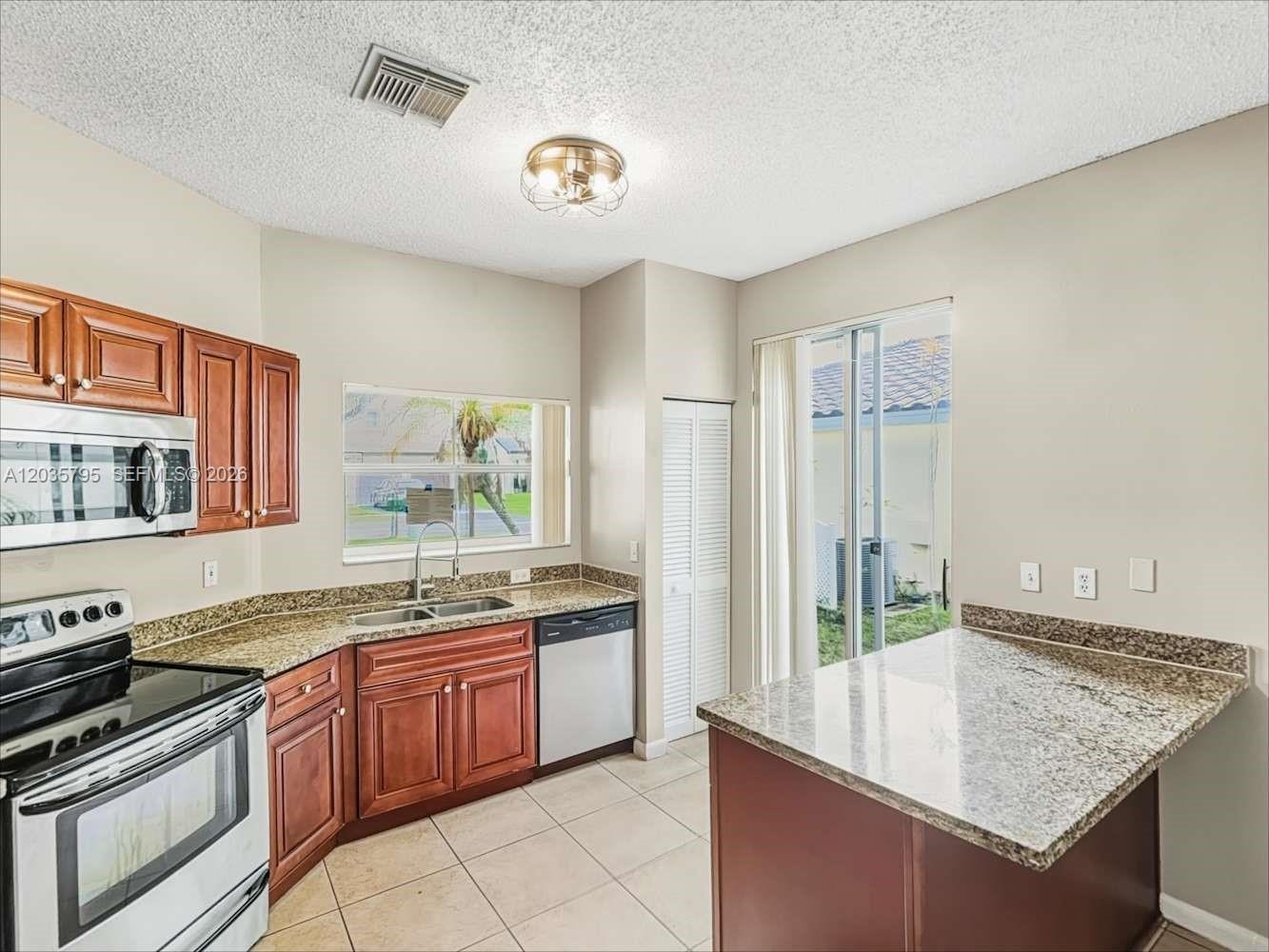 A kitchen with wood cabinets, granite countertops, a stainless steel oven, and a sliding door — PEMBROKE PINES, FL