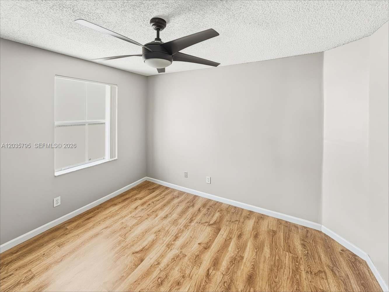 An empty bedroom features light gray walls, wood-look flooring, and a ceiling fan — PEMBROKE PINES, FL