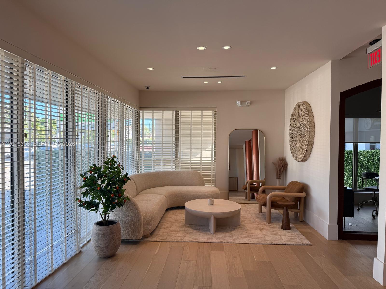 A modern living room features a curved sofa, round coffee table, and large floor mirror — 7320 Biscayne Blvd, Miami FL 33138, MIAMI, FL