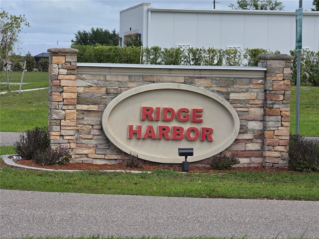 A stone monument sign with the text Ridge Harbor stands in a grassy landscape — 30086 CEDAR ROAD, PUNTA GORDA, FL