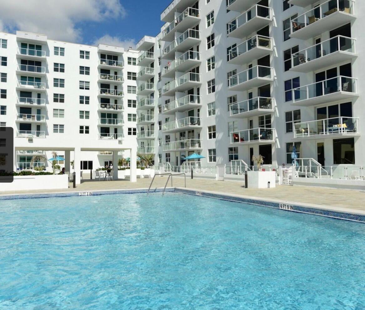 A swimming pool with depth markers sits in front of a multi-story white apartment building — 3450 S Ocean Boulevard # 224, Palm Beach FL 33480, PALM BEACH, FL