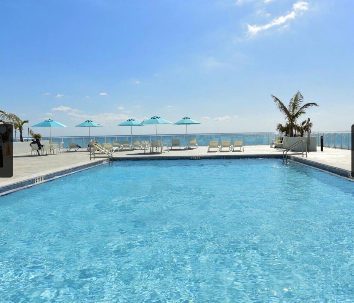 A rectangular swimming pool sits on a patio overlooking the ocean under a blue sky — 3450 S Ocean Boulevard # 224, Palm Beach FL 33480, PALM BEACH, FL