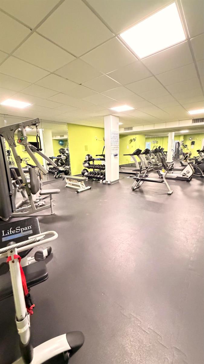 A gym room features various exercise machines, a weight rack, and lime green walls — 3450 S Ocean Boulevard # 224, Palm Beach FL 33480, PALM BEACH, FL