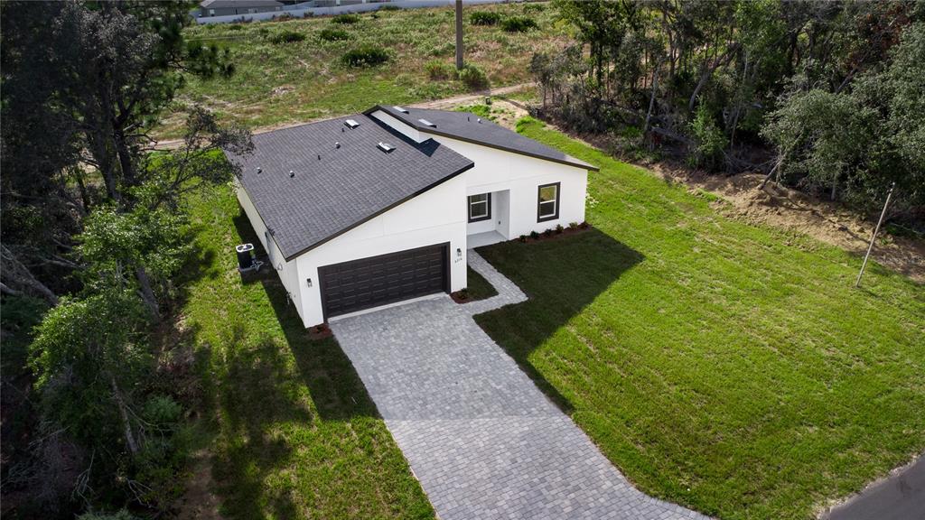 An aerial view shows a modern white house with a dark roof and paved driveway — 6216 SW 155TH STREET ROAD, OCALA, FL