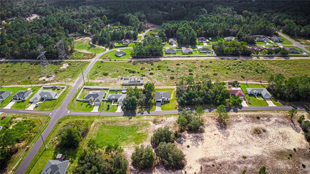 An aerial view shows a suburban neighborhood with houses, paved roads, and surrounding wooded areas — 6216 SW 155TH STREET ROAD, OCALA, FL