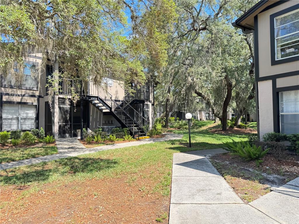 Exterior view of a two-story apartment building with a metal staircase and surrounding trees — 4033 DREAM OAK PLACE UNIT 101, TAMPA, FL