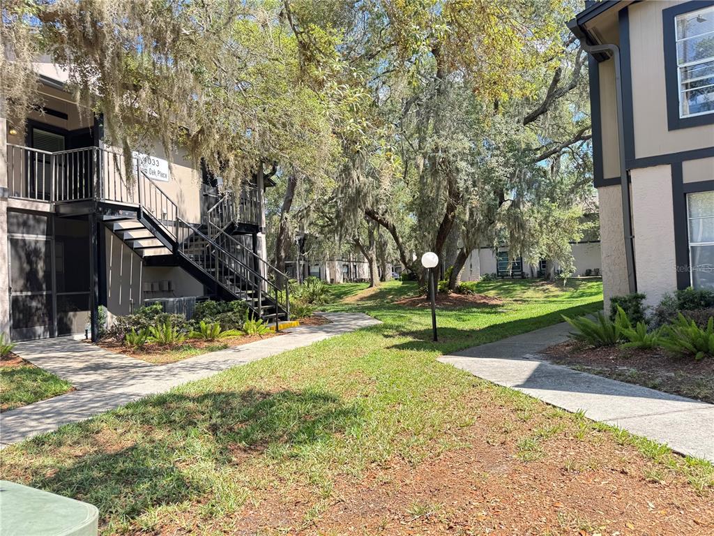 A view of apartment building exteriors with outdoor staircases and walkways surrounded by trees — 4033 DREAM OAK PLACE UNIT 101, TAMPA, FL