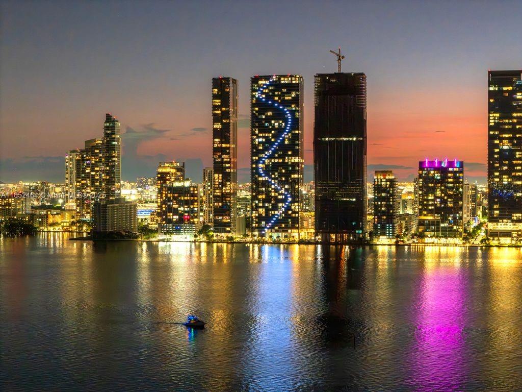 A wide-angle view of the Miami skyline at dusk with illuminated skyscrapers reflecting on water — 700 Ne 24th St # 4507, Miami FL 33137, MIAMI, FL