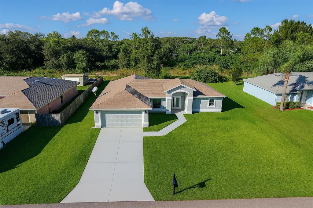 An aerial view of a single-story house with a tan roof, garage, and large lawn — 116 RIDGEMONT DRIVE, LEHIGH ACRES, FL