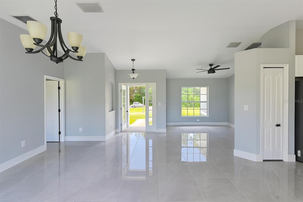 An open-concept living area features light gray walls, large glossy floor tiles, and a chandelier — 116 RIDGEMONT DRIVE, LEHIGH ACRES, FL