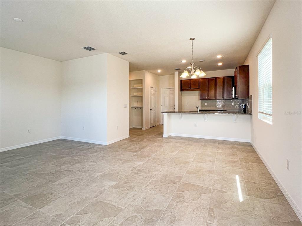 An open-concept kitchen with dark wood cabinets and a breakfast bar overlooks a tiled room — 10227 HIGHLINE CREST STREET, ORLANDO, FL