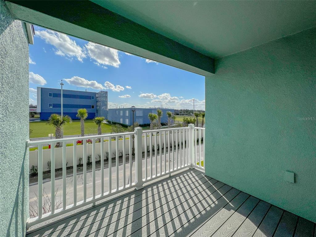A covered balcony with gray composite decking and a white railing overlooks a parking lot — 10227 HIGHLINE CREST STREET, ORLANDO, FL