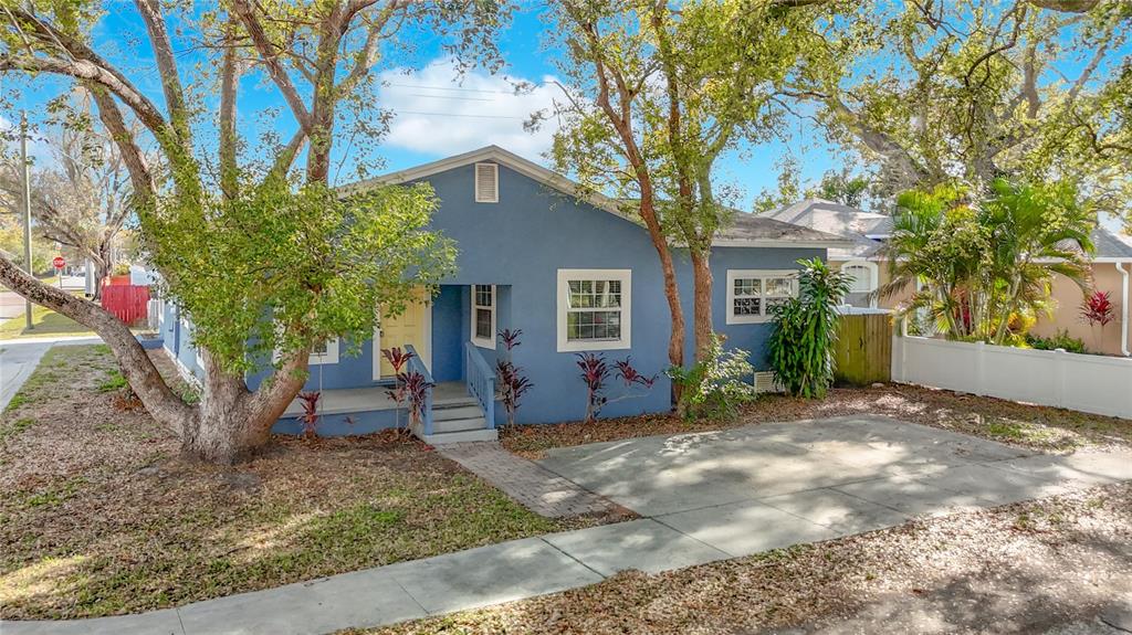 A blue, single-story house with a front porch, concrete driveway, and surrounding trees — 3002 W ARCH STREET, TAMPA, FL