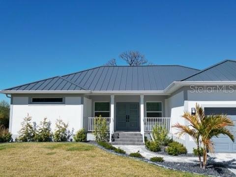 A single-story house with a metal roof, white stucco exterior, and a double front door — 1222 UNDERHILL CIRCLE, PORT CHARLOTTE, FL