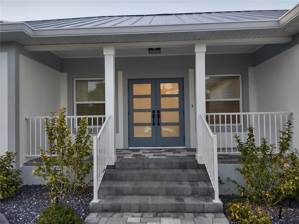 A gray house exterior features a double front door, white railings, and concrete steps — 1222 UNDERHILL CIRCLE, PORT CHARLOTTE, FL