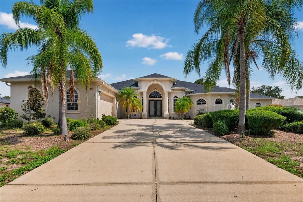 A single-story house with a concrete driveway, palm trees, and an arched entryway — 275 PLANTER ROAD, SPRING HILL, FL