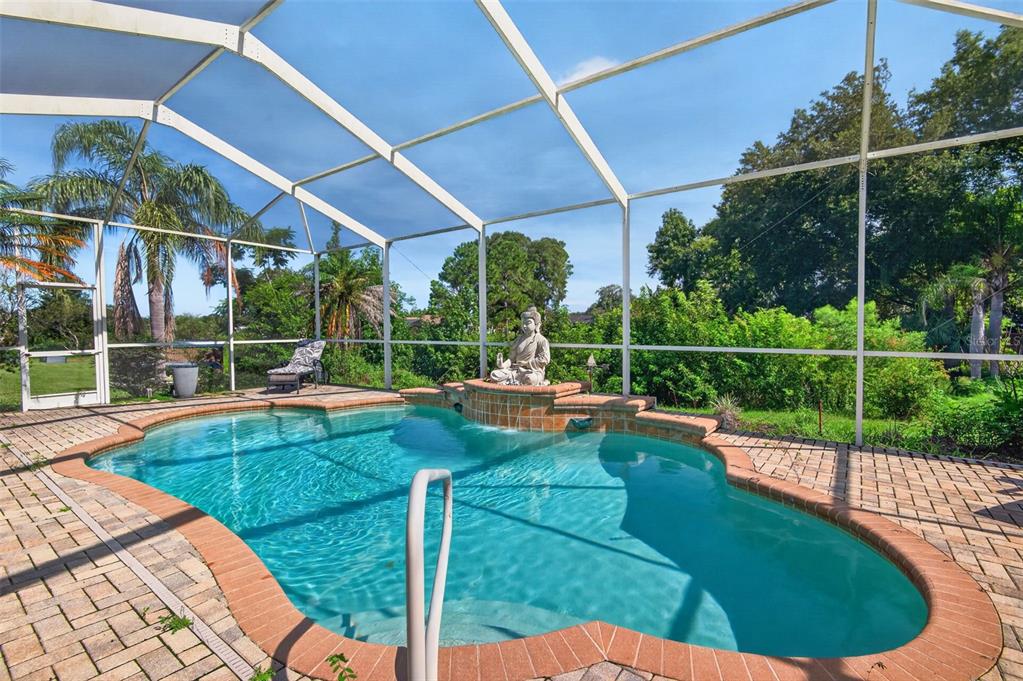 A screened-in swimming pool with a brick paver deck and a Buddha water feature — 275 PLANTER ROAD, SPRING HILL, FL