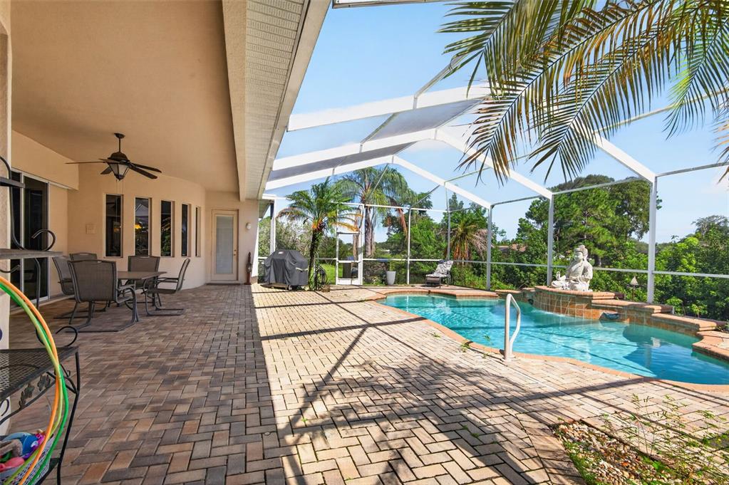 A screened-in patio features a brick paver deck, a swimming pool, and outdoor dining furniture — 275 PLANTER ROAD, SPRING HILL, FL