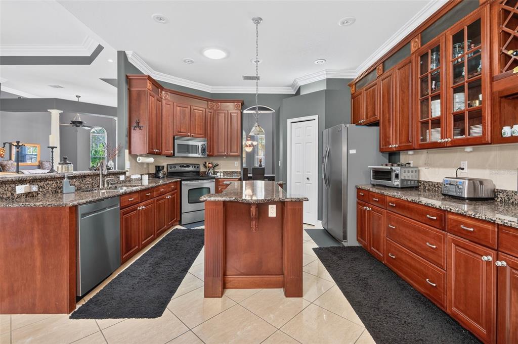 A kitchen with cherry wood cabinets, granite countertops, stainless steel appliances, and a central island — 275 PLANTER ROAD, SPRING HILL, FL
