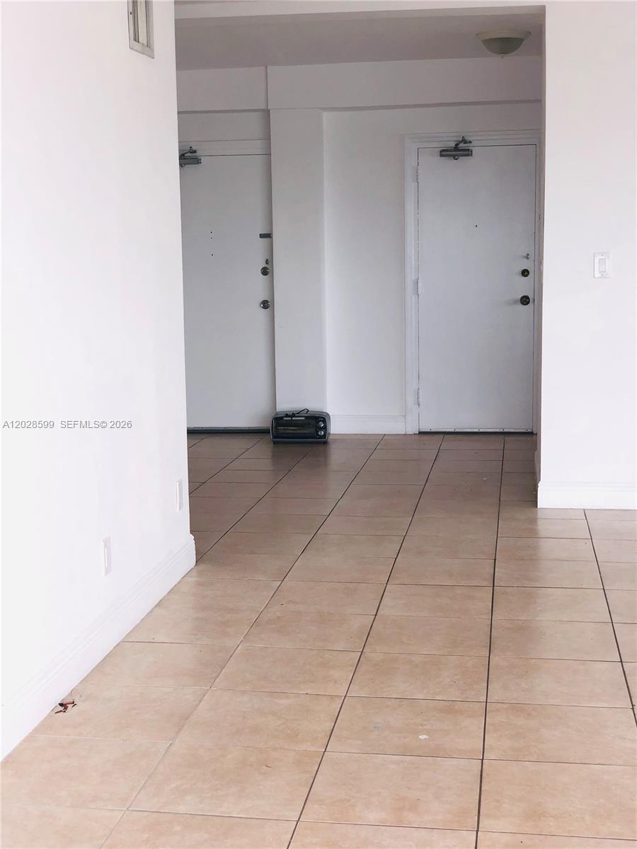 A hallway with light-colored tile flooring leads to two white doors — 1430 Brickell Bay Dr # 5, Miami FL 33131, MIAMI, FL