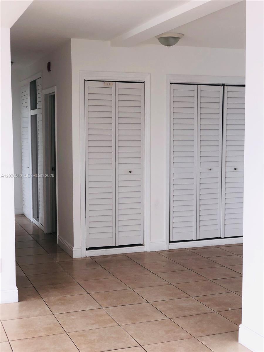 A hallway features tiled floors, white walls, and two sets of louvered closet doors — 1430 Brickell Bay Dr # 5, Miami FL 33131, MIAMI, FL