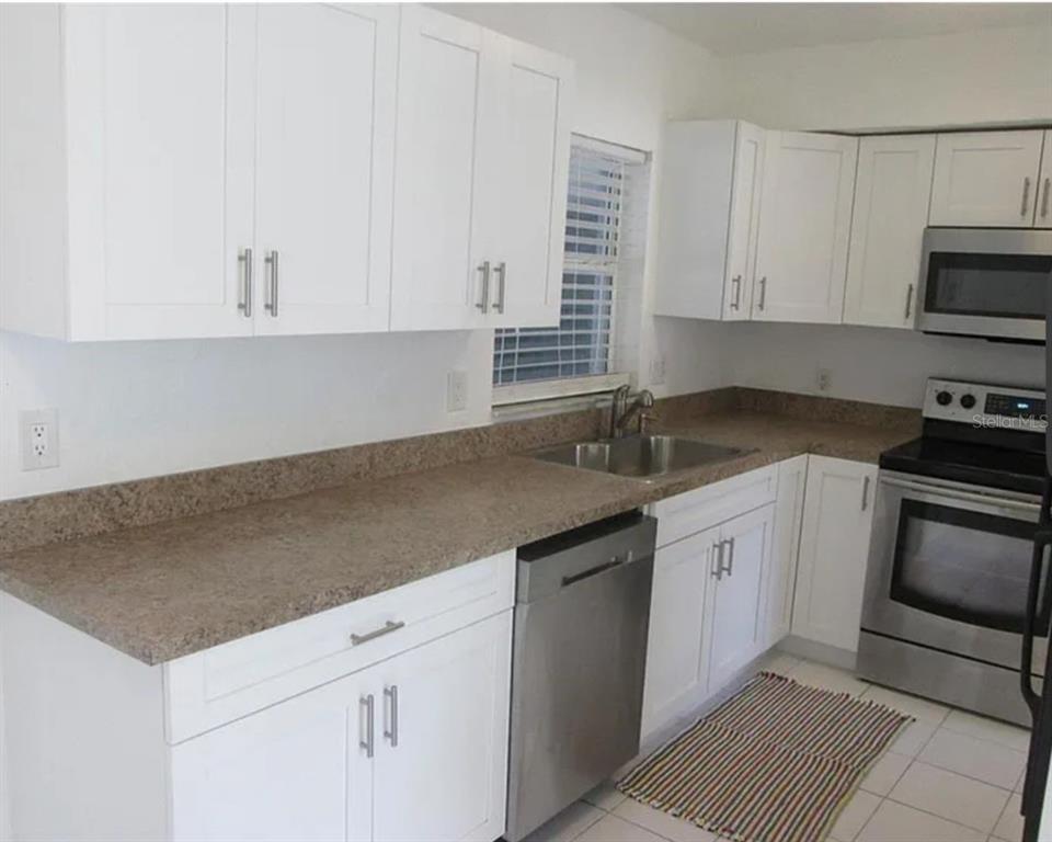 A kitchen with white cabinets, stainless steel appliances, and brown speckled laminate countertops — 5901 28TH STREET N, ST PETERSBURG, FL