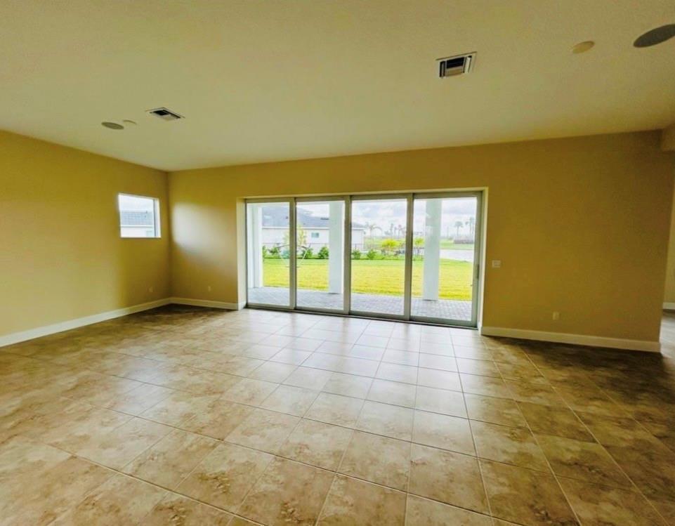 An empty room with tan walls, tile flooring, and a large sliding glass door — 5199 Liberty Lane, Westlake FL 33470, WESTLAKE, FL