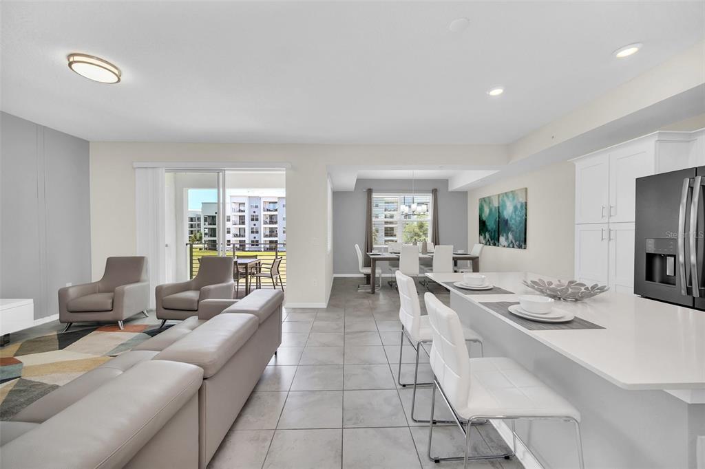 An open-concept living and dining area features tile flooring, white cabinetry, and a kitchen island — 3180 PARADOX CIRCLE UNIT 203, KISSIMMEE, FL