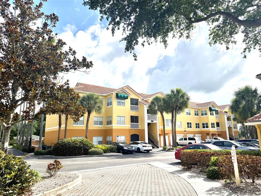A multi-story yellow apartment building with palm trees and a parking lot in front — 10764 70TH AVENUE UNIT #1201, SEMINOLE, FL