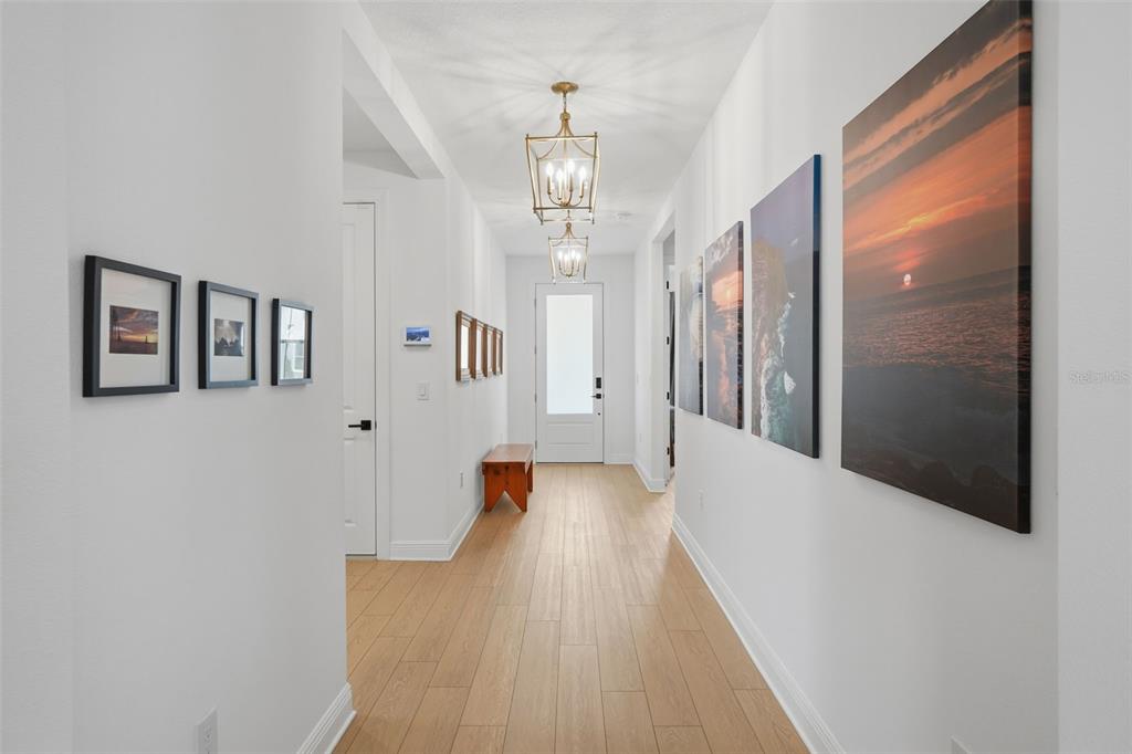 A bright hallway features light wood flooring, two hanging lanterns, and framed wall art — 1658 PINECLIFF DRIVE, APOPKA, FL