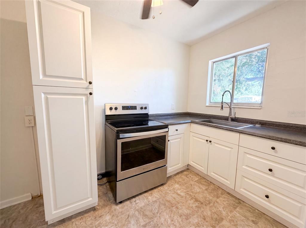 A kitchen features white cabinets, a stainless steel stove, and a sink under a window — 2235 45TH AVENUE N, ST PETERSBURG, FL