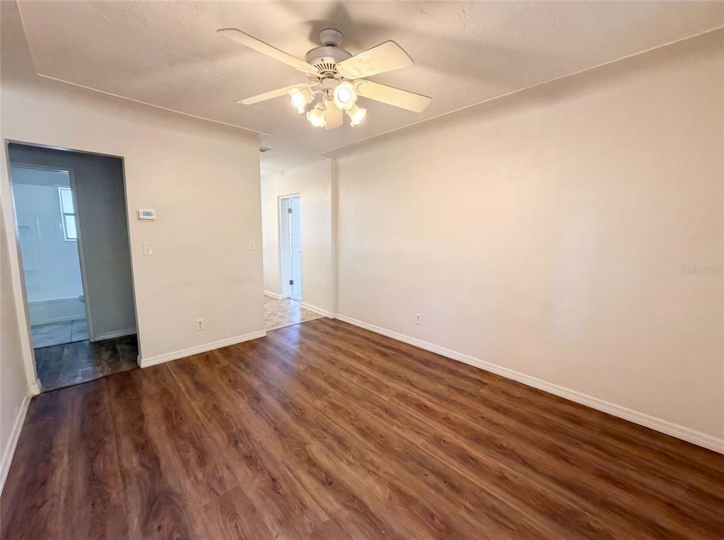 A living room with wood-look flooring, a ceiling fan, and doorways leading to other rooms — 2235 45TH AVENUE N, ST PETERSBURG, FL