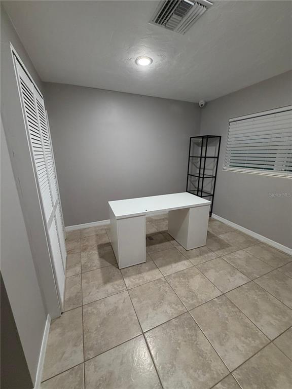 A small room with gray walls, tile flooring, a white desk, and a black shelf — 5950 HIGH STREET, NEW PORT RICHEY, FL