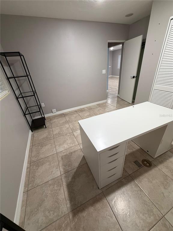 A home office features a white desk, a black metal shelving unit, and tile flooring — 5950 HIGH STREET, NEW PORT RICHEY, FL
