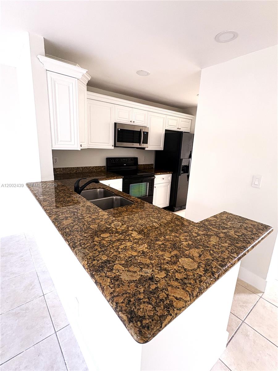 A kitchen features white cabinets, dark granite countertops, and black appliances — 3743 NW 122nd Ter, Sunrise FL 33323, SUNRISE, FL