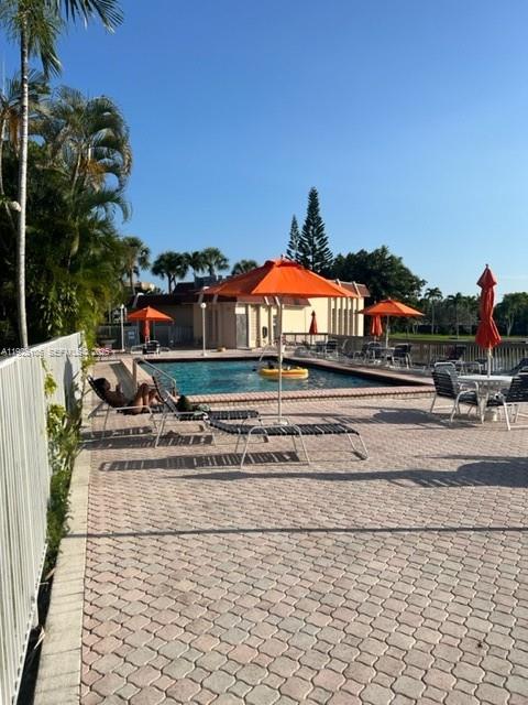 A swimming pool area features lounge chairs, orange umbrellas, and a paved deck — 2001 Atlantic Shores Blvd # 105, Hallandale Beach FL 33009, HALLANDALE BEACH, FL