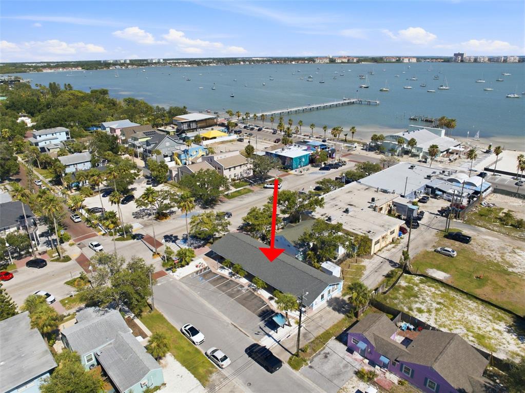 An aerial view shows a single-story building with a parking lot near a waterfront area — 3101 BEACH BOULEVARD S UNIT 1-5, GULFPORT, FL