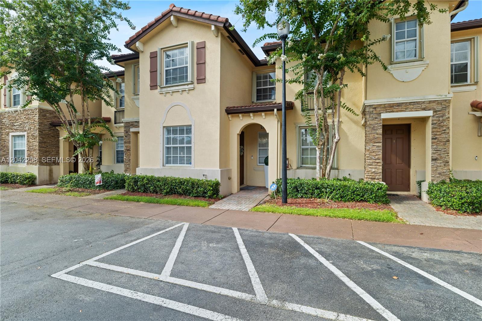 A two-story townhouse exterior features tan stucco walls, stone accents, and a paved walkway — 3370 NE 14th Dr # 29, Homestead FL 33033, HOMESTEAD, FL
