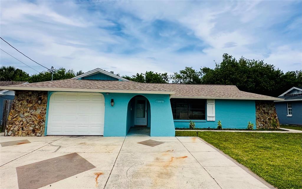 A single-story house with bright blue siding, a stone facade, and a white garage door — 12816 1ST ISLE, HUDSON, FL