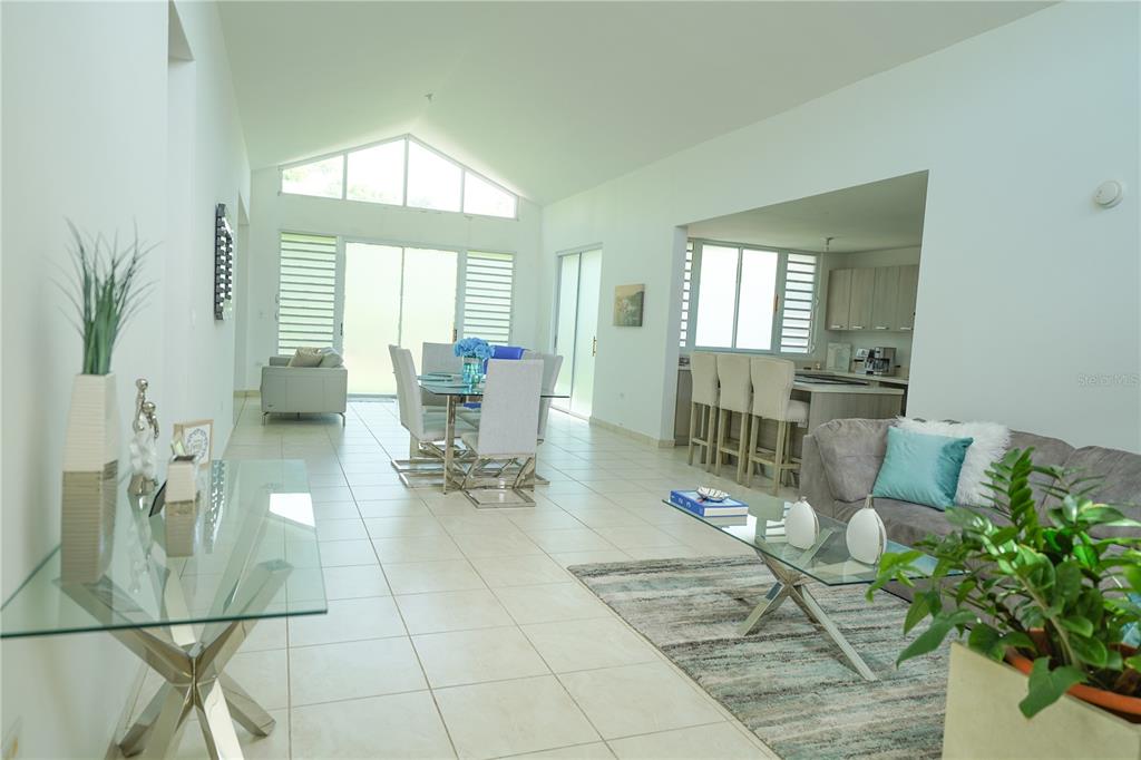 An open-concept living and dining area features vaulted ceilings, tile flooring, and a modern kitchen — Calle Ruisenor MIRAMELINDA ESTATES UNIT 223, RIO GRANDE, PR
