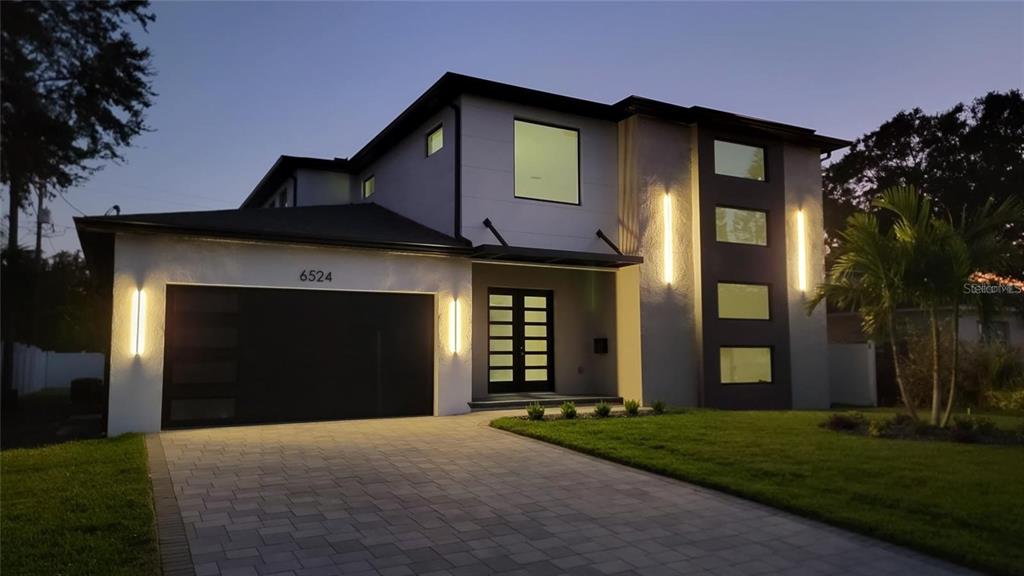 A modern two-story house exterior features a dark garage door, vertical lighting, and paved driveway — 6524 6TH AVENUE N, ST PETERSBURG, FL