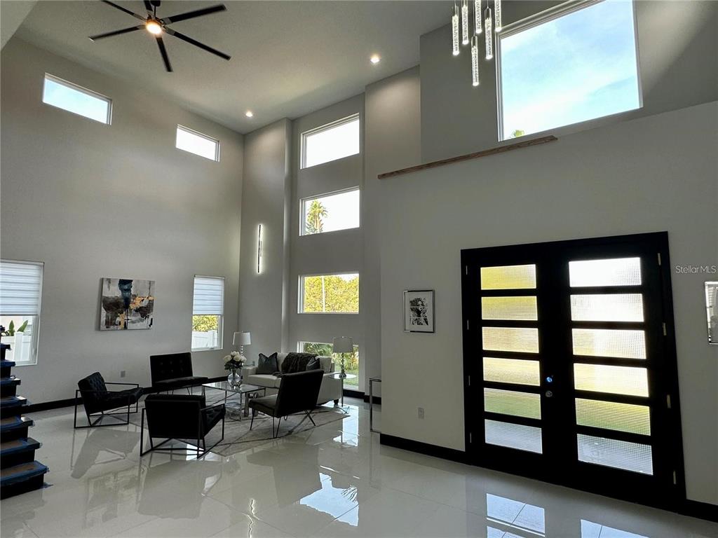 A spacious living room features high ceilings, large windows, tile flooring, and a double front door — 6524 6TH AVENUE N, ST PETERSBURG, FL