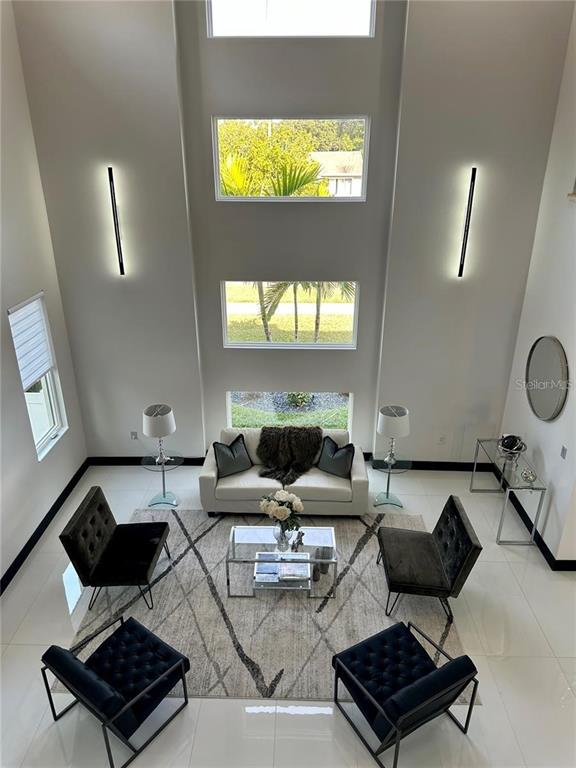 A high-ceilinged living room features a sofa, four chairs, a coffee table, and tall windows — 6524 6TH AVENUE N, ST PETERSBURG, FL