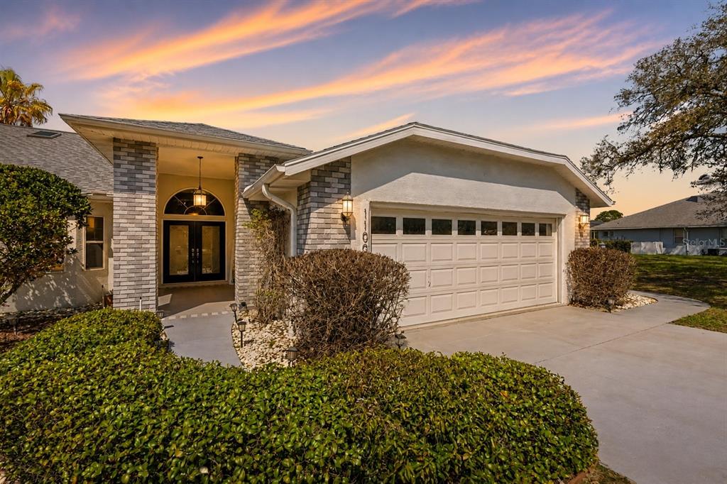 A single-story house features a brick facade, a two-car garage, and a covered entryway — 11009 WOODLAND WATERS BOULEVARD, WEEKI WACHEE, FL