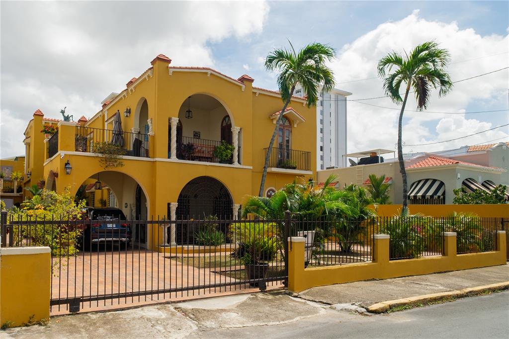 A two-story yellow stucco house with arched entryways, a gated driveway, and palm trees — 711 CONCORDIA ST., MIRAMAR DEV., SAN JUAN, PR