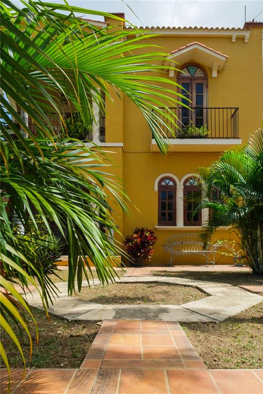 A yellow two-story house features a balcony, arched windows, and a tiled walkway — 711 CONCORDIA ST., MIRAMAR DEV., SAN JUAN, PR