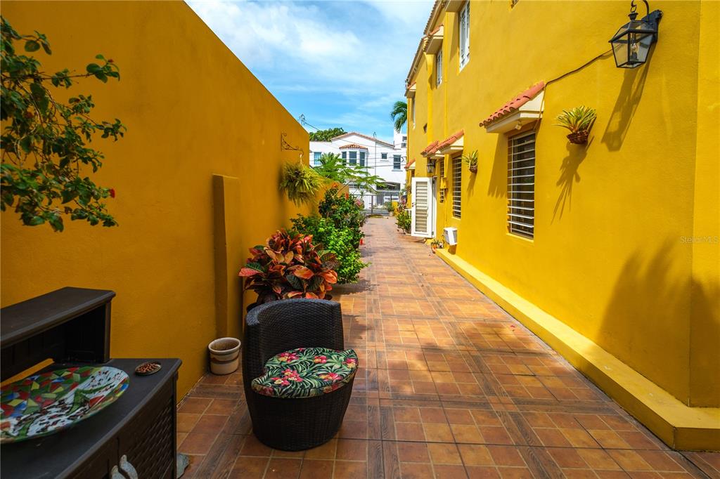 A narrow outdoor walkway with tiled flooring sits between two bright yellow exterior walls — 711 CONCORDIA ST., MIRAMAR DEV., SAN JUAN, PR