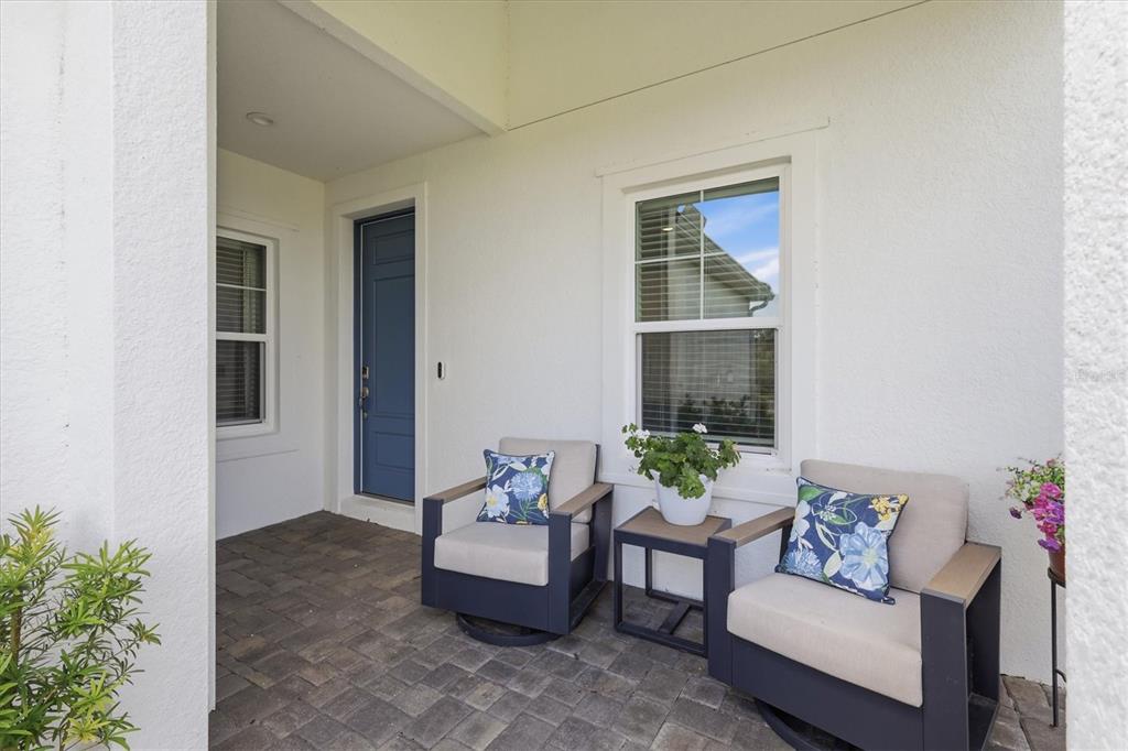 A covered front porch features two chairs, a small table, and a blue front door — 12650 PALATKA DRIVE, VENICE, FL
