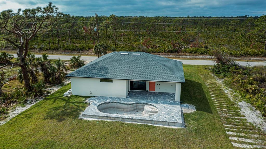 An aerial view of a house with a green roof, patio, and an empty swimming pool — 22528 MINERVA AVENUE, PORT CHARLOTTE, FL