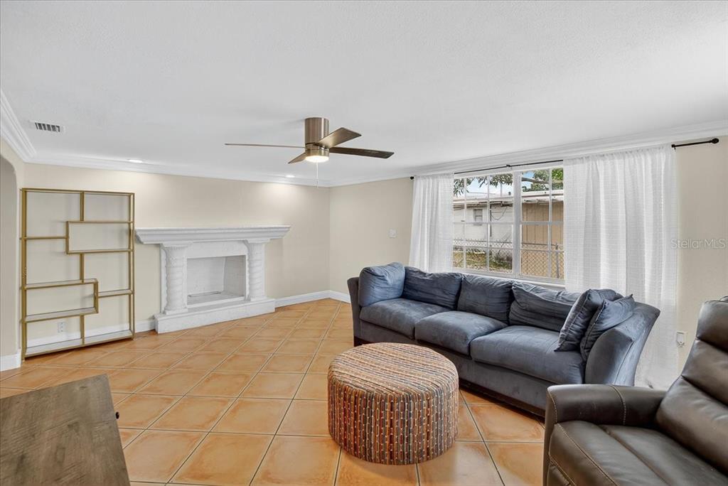A living room features a fireplace, a blue sofa, a round ottoman, and tile flooring — 4515 W NORTH STREET, TAMPA, FL